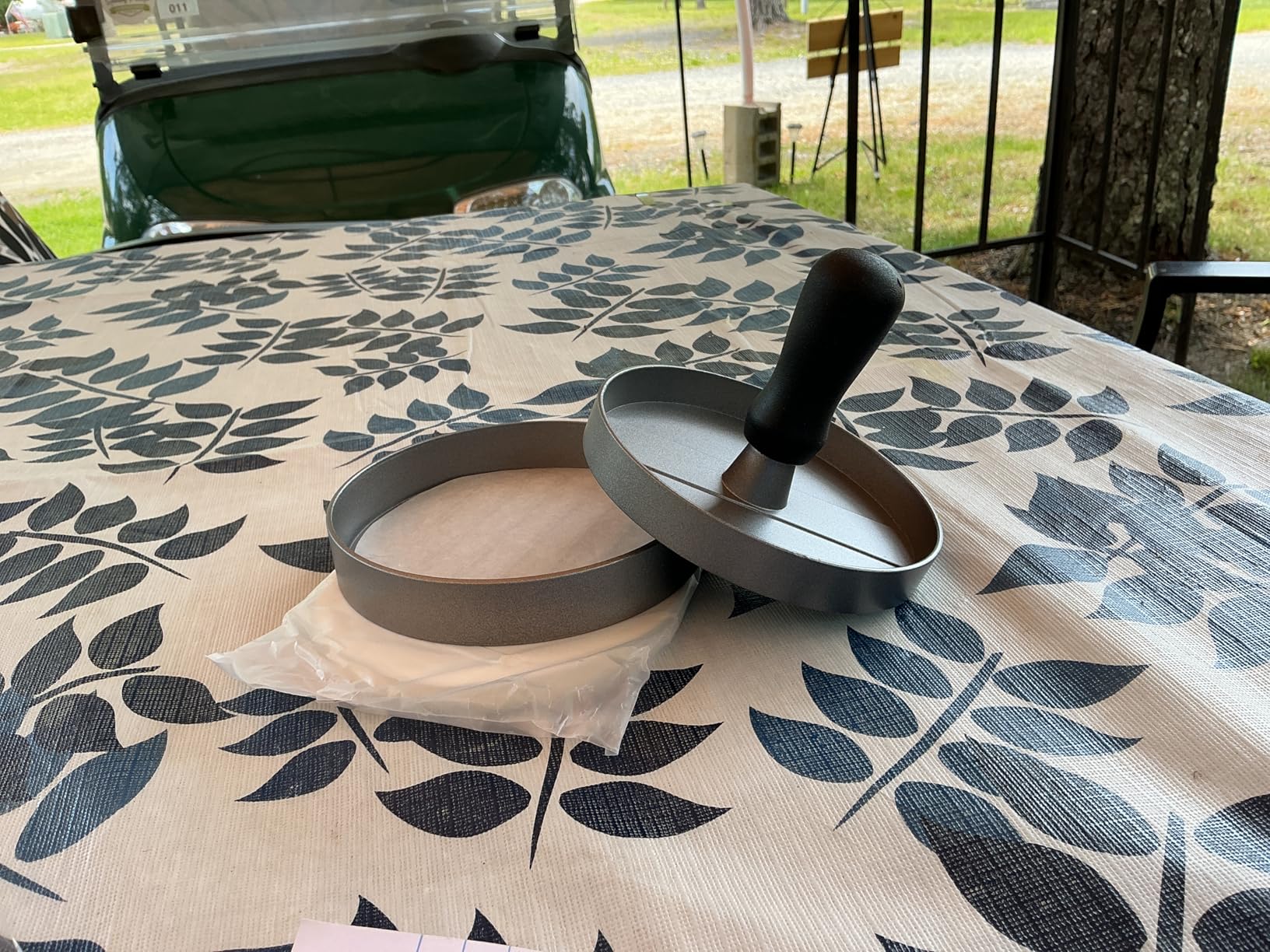 Burger press and patty papers on an outdoor table