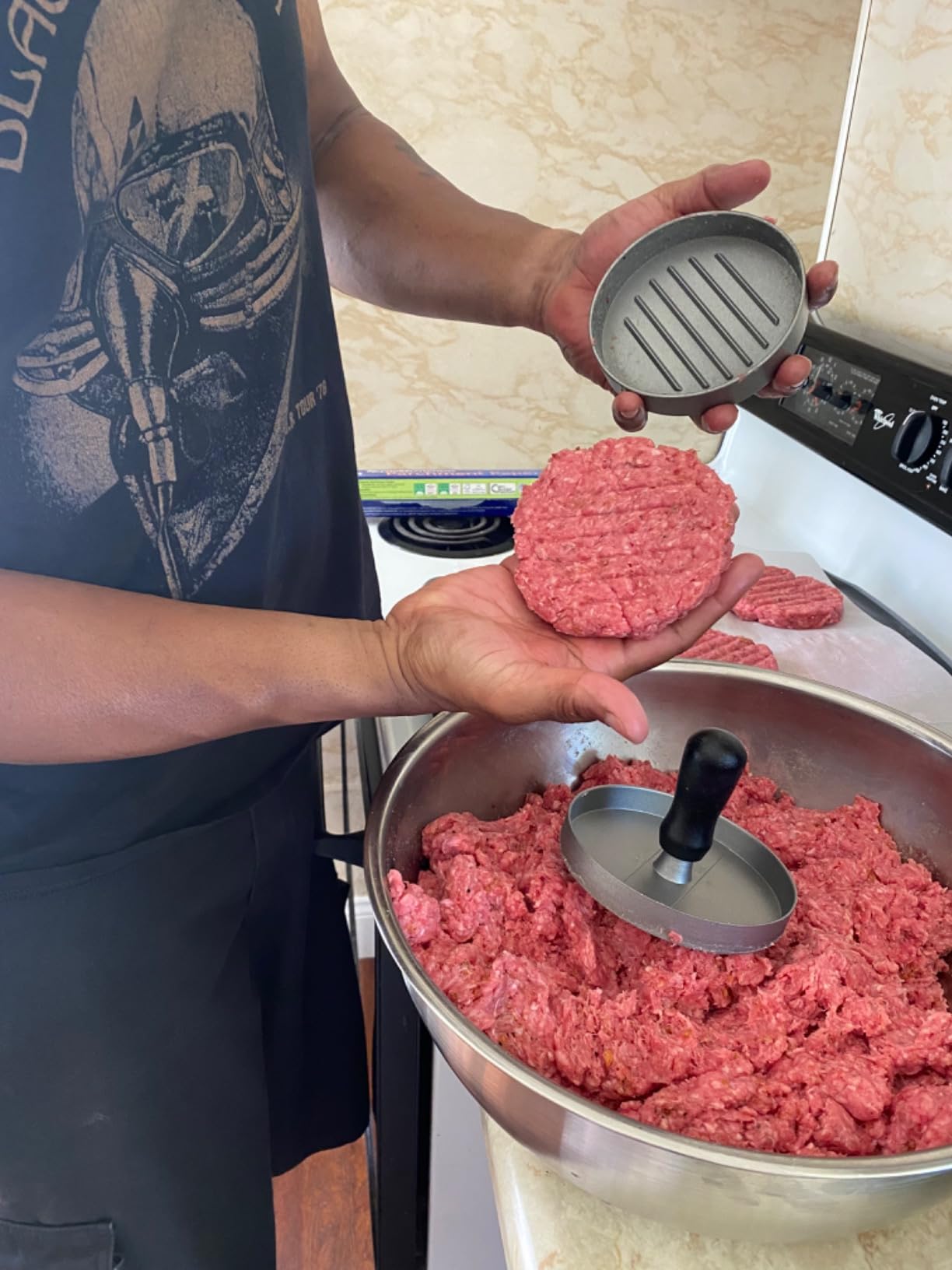 Customer holding a pressed burger patty beside the burger press