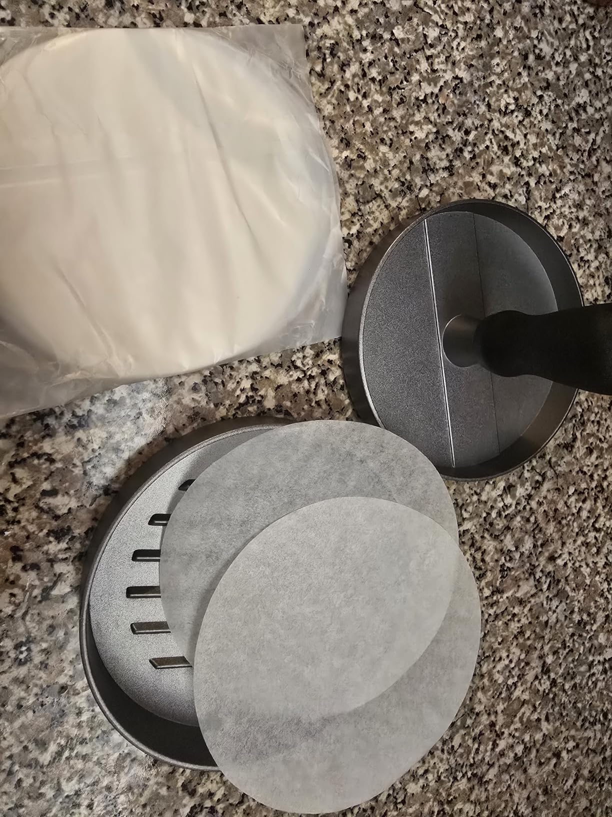 Burger press set with round patty papers on a kitchen counter